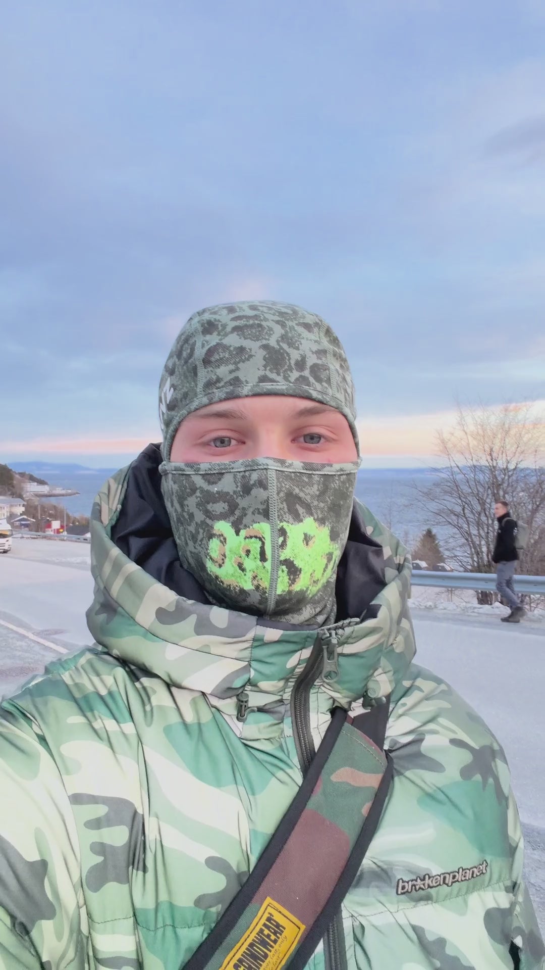 LUVZ CAMO heat-reactive balaclava worn outdoors in the snow — the camo shell shifts to light green where body heat touches it